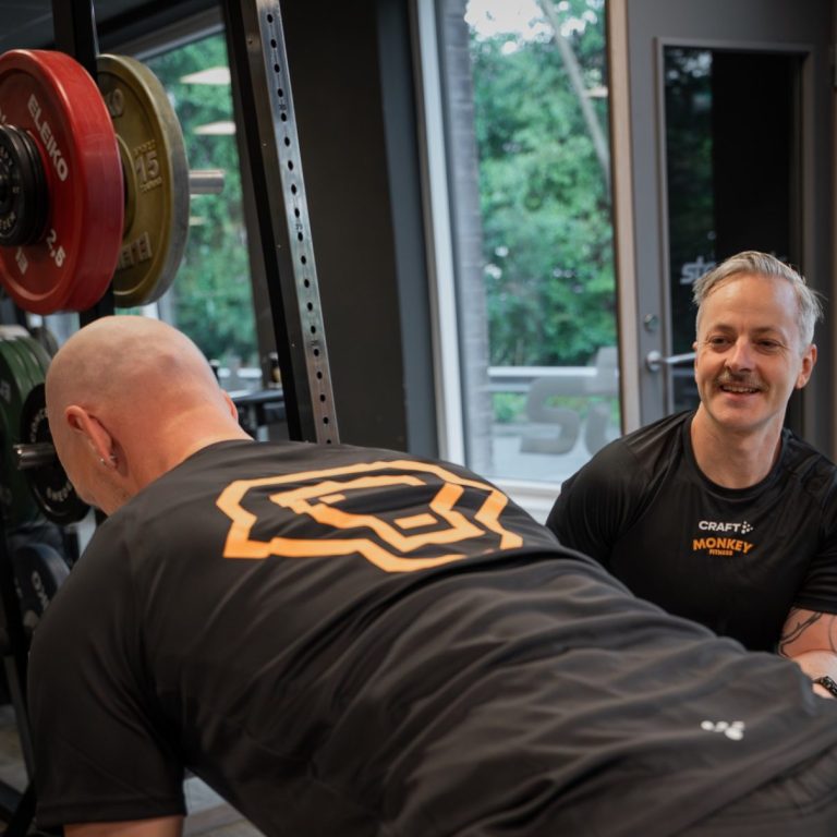 Personlig tränare hjälper klient med styrketräning på gym i Göteborg
